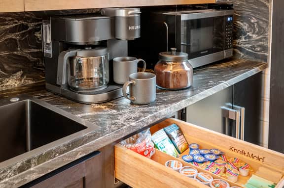 Stocked coffee bar: Keurig duo, mugs, microwave, and snacks at the ready