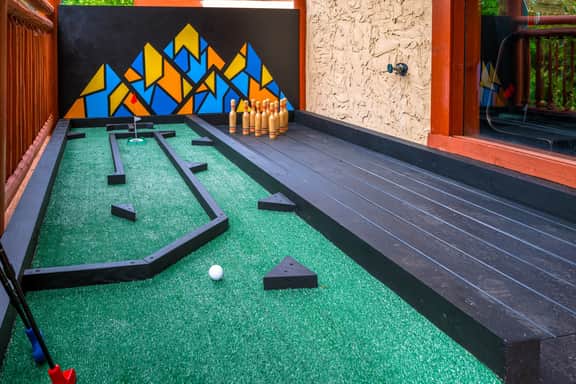 Playful outdoor mini golf deck with colorful mural and games