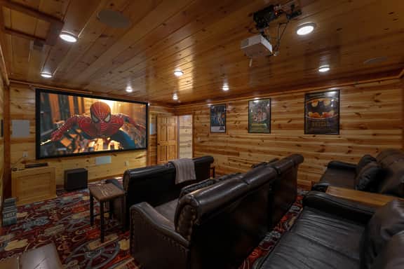 Cozy wood-paneled home theater with big screen and plush recliner seating